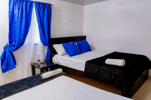 a bedroom with two beds and a window with blue curtains at Secretos del Eden in Ruiosucio