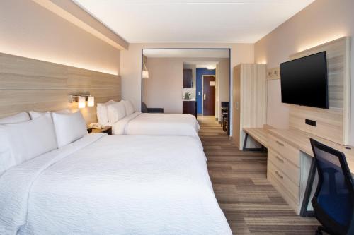 a hotel room with two beds and a flat screen tv at Holiday Inn Express Hotel & Suites Rochester Webster by IHG in Webster