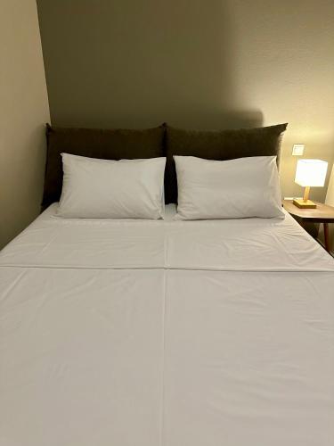 a bed with two white pillows and a table with a lamp at SnappyB Living Spaces in Alexandroupoli