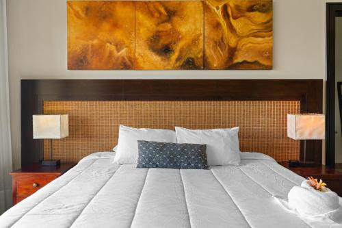 a bedroom with a large white bed with a painting on the wall at Villa Buena Onda All Inclusive in Coco