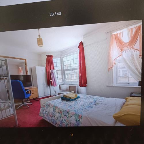 1 dormitorio con 1 cama y 2 ventanas con cortinas rojas en King-size room in house en Londres