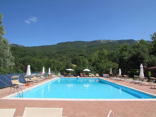 ein großer Pool mit Stühlen und Sonnenschirmen in der Unterkunft Albergo Lago Verde in Pennabilli