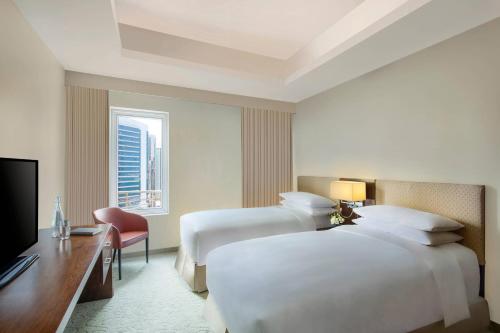 a hotel room with two beds and a television at Marriott Executive Apartments City Center Doha in Doha