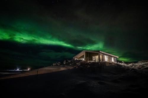 a house under the northern lights at night at Mörk Superior Cottages in Hvammstangi