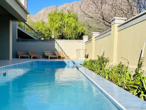 a swimming pool with blue water next to a building at Calais Guest House in Franschhoek