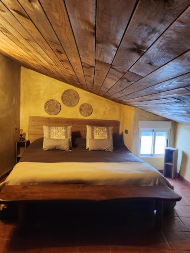 a bedroom with a large bed with a wooden ceiling at Buhardilla rústica muy acogedora in Villahermosa del Río