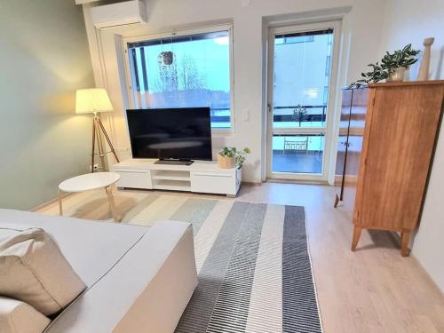 sala de estar con TV de pantalla plana y sofá en Moderni kaksio keskustassa, oma sauna!, en Uusikaupunki