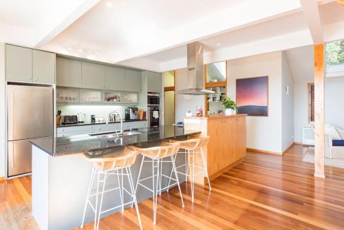 a kitchen with a large island with bar stools at Private Luxury in Paihia - with Heated Pool! in Paihia