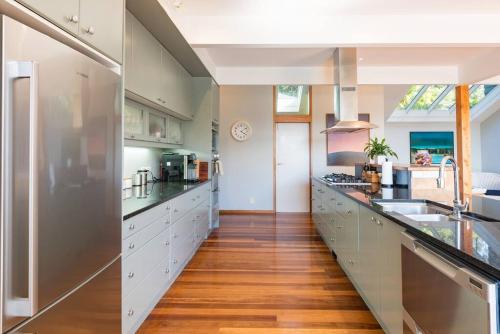 a large kitchen with stainless steel appliances and wood floors at Private Luxury in Paihia - with Heated Pool! in Paihia