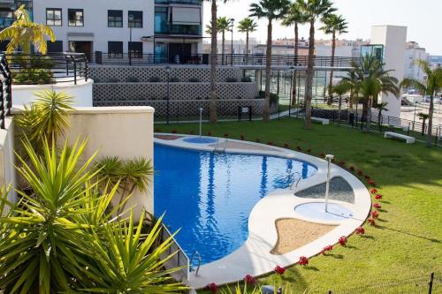 una piscina en un patio con palmeras en La Bahia - Gelijkvloers appartement, en Santa Pola