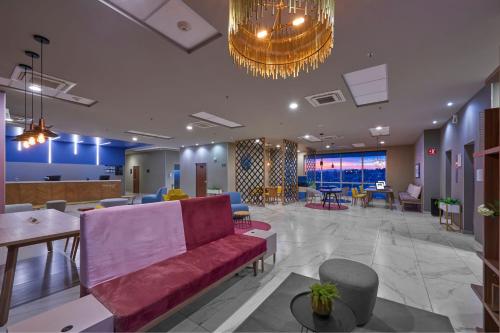 a lobby with a red couch and tables and chairs at City Express Plus by Marriott Ciudad de México Mundo E in Mexico City