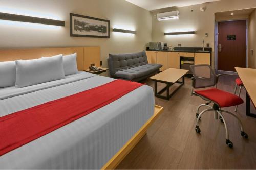 a hotel room with a bed and a desk and chairs at City Express Plus by Marriott Ciudad de México Mundo E in Mexico City