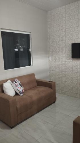 Sofá marrón en la sala de estar con ventana en Sua casa completa em Viçosa do Ceará en Viçosa do Ceará