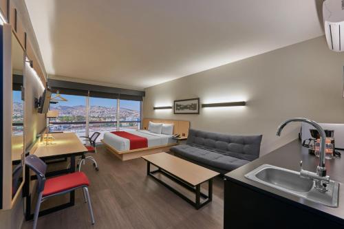 uma sala de estar com um sofá e uma cama num quarto em City Express Plus by Marriott Mundo E em Cidade do México