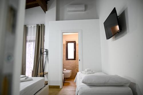a bedroom with two beds and a television on the wall at Borgo Caridà - Green Family Holidays in Zaccanopoli