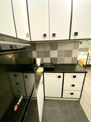 a kitchen with white cabinets and a black counter top at Allegro Apartment Free Parking in Novi Sad
