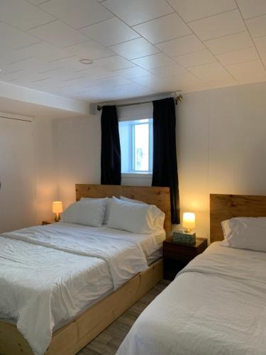 a bedroom with two beds and two lamps on tables at Maison Charles Edmond in Grandes-Bergeronnes