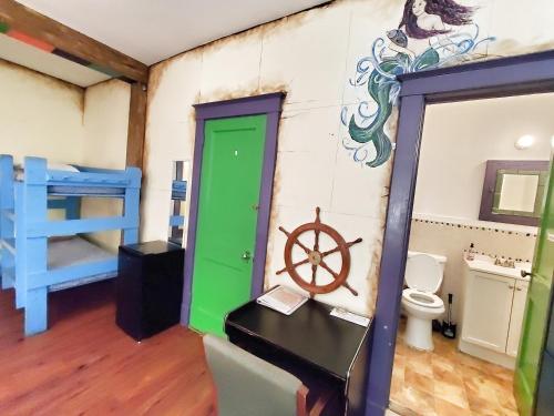 a room with a green door and a room with a toilet at The Pirate Haus Inn in Saint Augustine