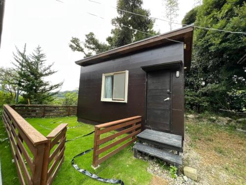 a black tiny house with a door and a bench at Oasis Minamiboso - Vacation STAY 04676v in Minamiboso