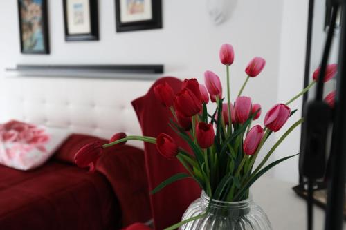 a vase filled with red tulips in front of a red couch at B&B Royal Palace of Napoli & Reggia di Caserta in Caserta