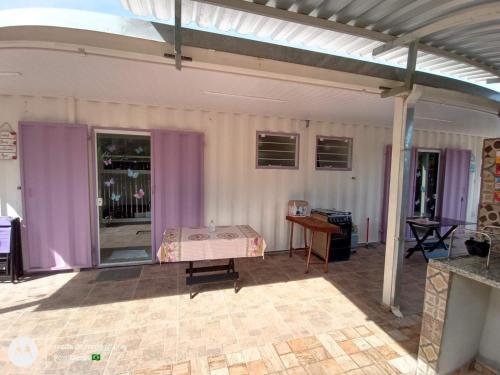 a patio with a bed in a room with purple curtains at Chalé 1 Container Ubatuba Ruínas da Lagoinha Praia da Lagoinha in Ubatuba