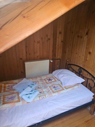 a bed in a room with a wooden wall at Restoran Domaćin in Bosanski Novi