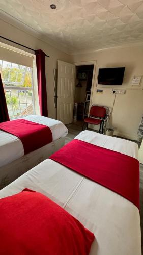 a bedroom with two beds with red and white sheets at The Railway Sleeper Lodge in Colchester