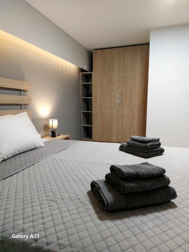 1 dormitorio con 1 cama con toallas plegables. en Square Apartments, en Tríkala