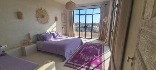 - une chambre avec un lit violet et une fenêtre dans l'établissement Lalla Essaouira, Villa Najma avec piscine pour 10 personnes, à Essaouira