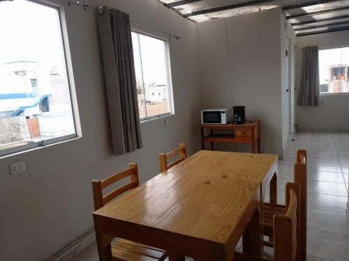 a dining room with a wooden table and some windows at POSADA SALAS & KARI PERU TRAVEL in Mollendo