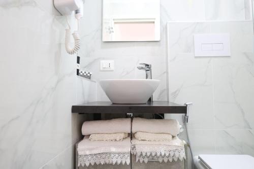 a bathroom with a sink and towels on a shelf at B&B Royal Palace of Napoli & Reggia di Caserta in Caserta