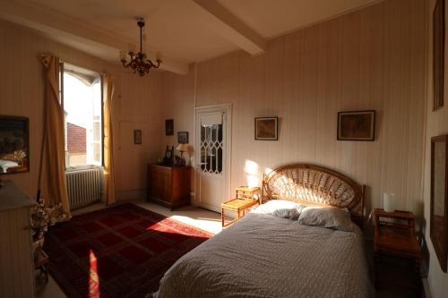 een slaapkamer met een bed en een raam bij Ancien presbytere au coeur du village in Mauvezin