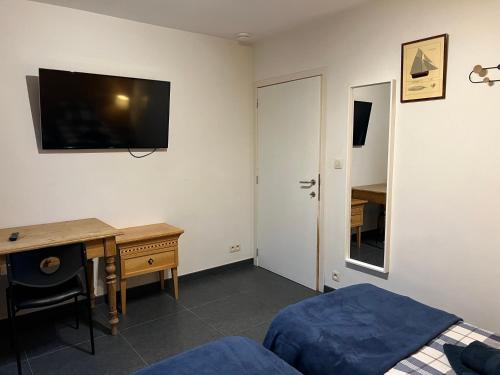 1 dormitorio con escritorio, 1 cama y TV en la pared en Dame Cerise, en Wavre