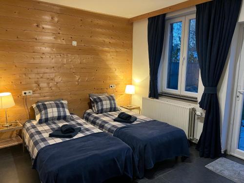 two beds in a room with wooden walls and windows at Dame Cerise in Wavre