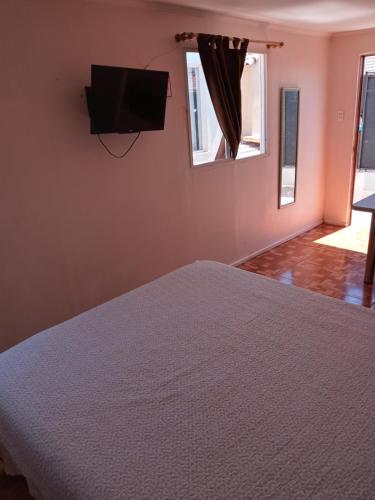 a bedroom with a bed and a flat screen tv at Hospedaje Walgün in La Serena