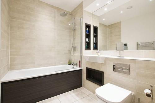 a bathroom with a tub and a toilet and a sink at Greenwich O2 Apartment in London