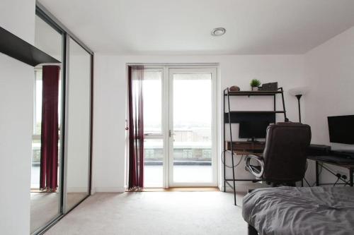 Greenwich O2 Apartment في لندن: غرفة نوم بسرير ومكتب ونافذة