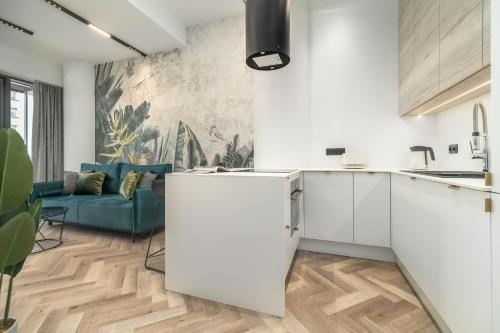 eine Küche mit weißen Schränken und einer blauen Couch in der Unterkunft Comfy Apartments 4-5th Floor Hanza Tower - Sauna & Pool in Stettin