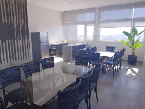 a dining room with tables and chairs and a kitchen at Nuevo, céntrico y acogedor dpto in Concepción