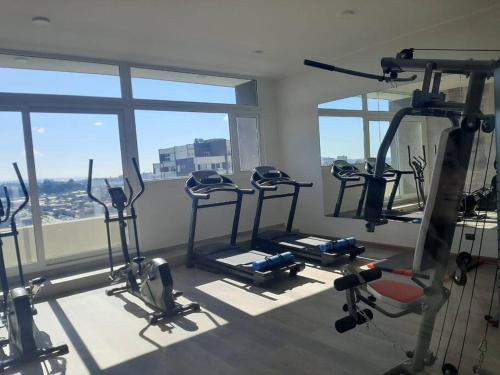 un gimnasio con varias máquinas de correr en una habitación con ventanas en Nuevo, céntrico y acogedor dpto, en Concepción