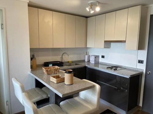 a kitchen with a counter with chairs and a sink at Nuevo, céntrico y acogedor dpto in Concepción