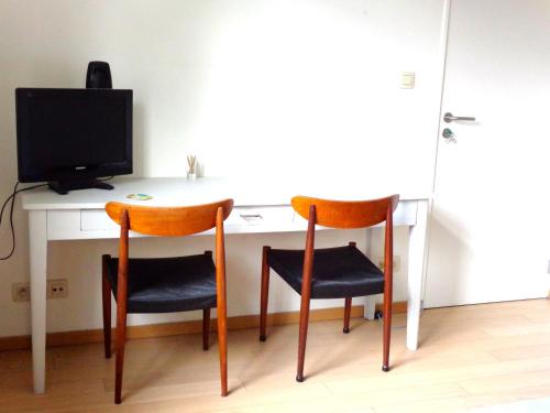 a room with a desk with two chairs and a television at B&B La Chambre du Zodiaque in Brussels