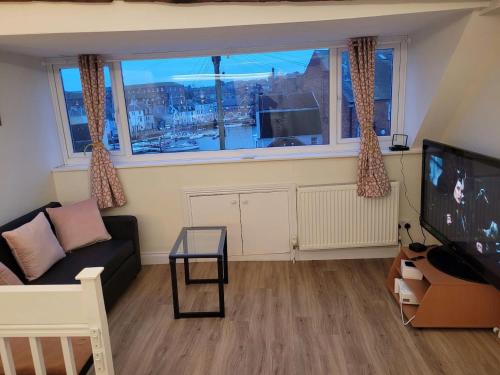 a living room with a couch and a large window at Beach & Harbour View House in Weymouth