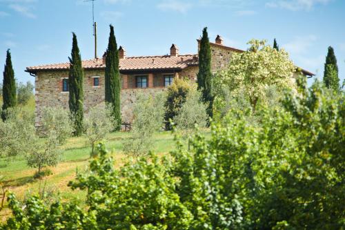 a building in the middle of a field with trees at Agriturismo Podere Campaini in Volterra