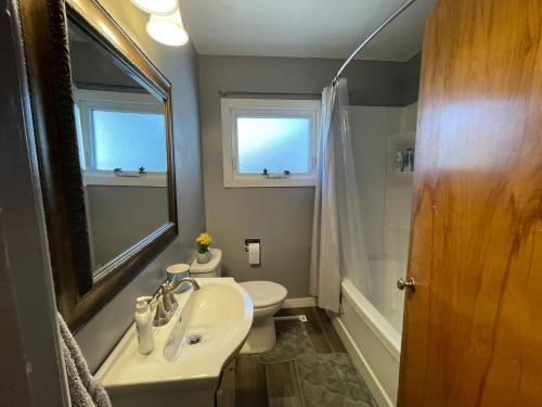 La salle de bains est pourvue d'un lavabo, de toilettes et d'un miroir. dans l'établissement TheSunshine: Bright&Peaceful 2 Bdrm Character Home, à Saskatoon