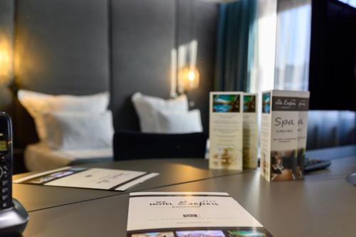 a desk in a hotel room with a table with a room with a bed at Spa Hotel Ezeretz Blagoevgrad in Blagoevgrad