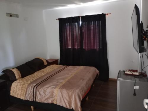 1 dormitorio con cama y cortina negra en Hermosa casa en Lomas Del Rey en San Antonio de Arredondo