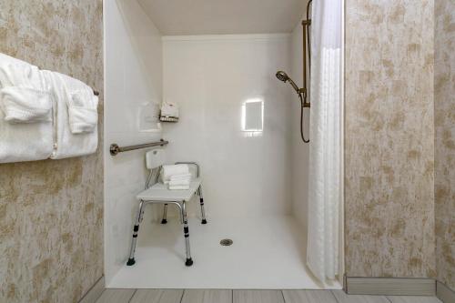 a white bathroom with a chair and a shower at Comfort Inn in Missoula