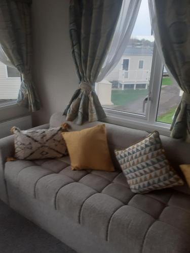 a couch with pillows sitting in front of a window at Littlesea Haven Weymouth in Weymouth