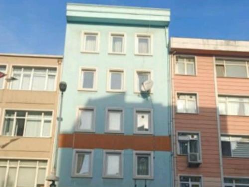 wysoki niebieski budynek przed niektórymi budynkami w obiekcie The Sweet Building Esso w Stambule